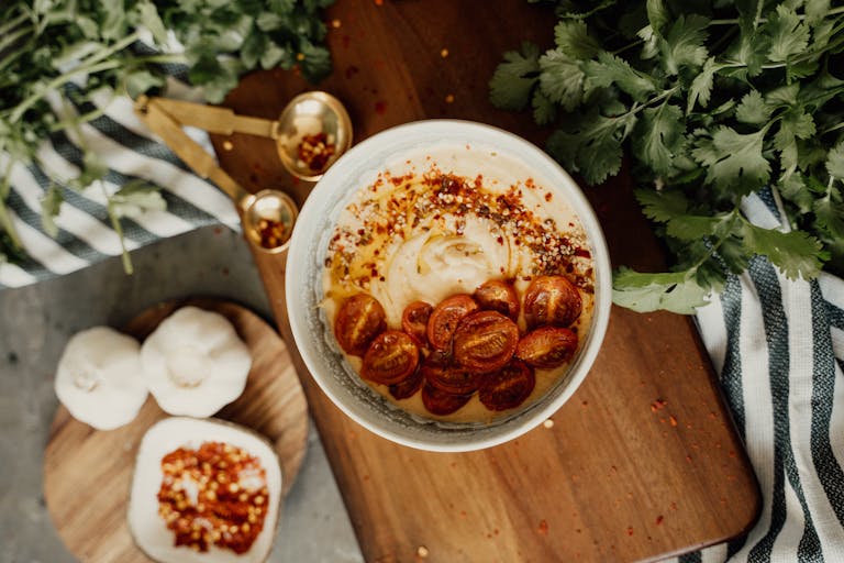 A delicious bowl of hummus topped with cherry tomatoes and spices, perfect for a vegan snack.