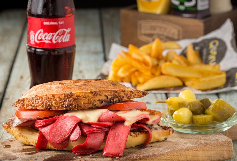 Mouth-watering sandwich with pickles and fries, served with Coca Cola in Sarıyer, Turkey.