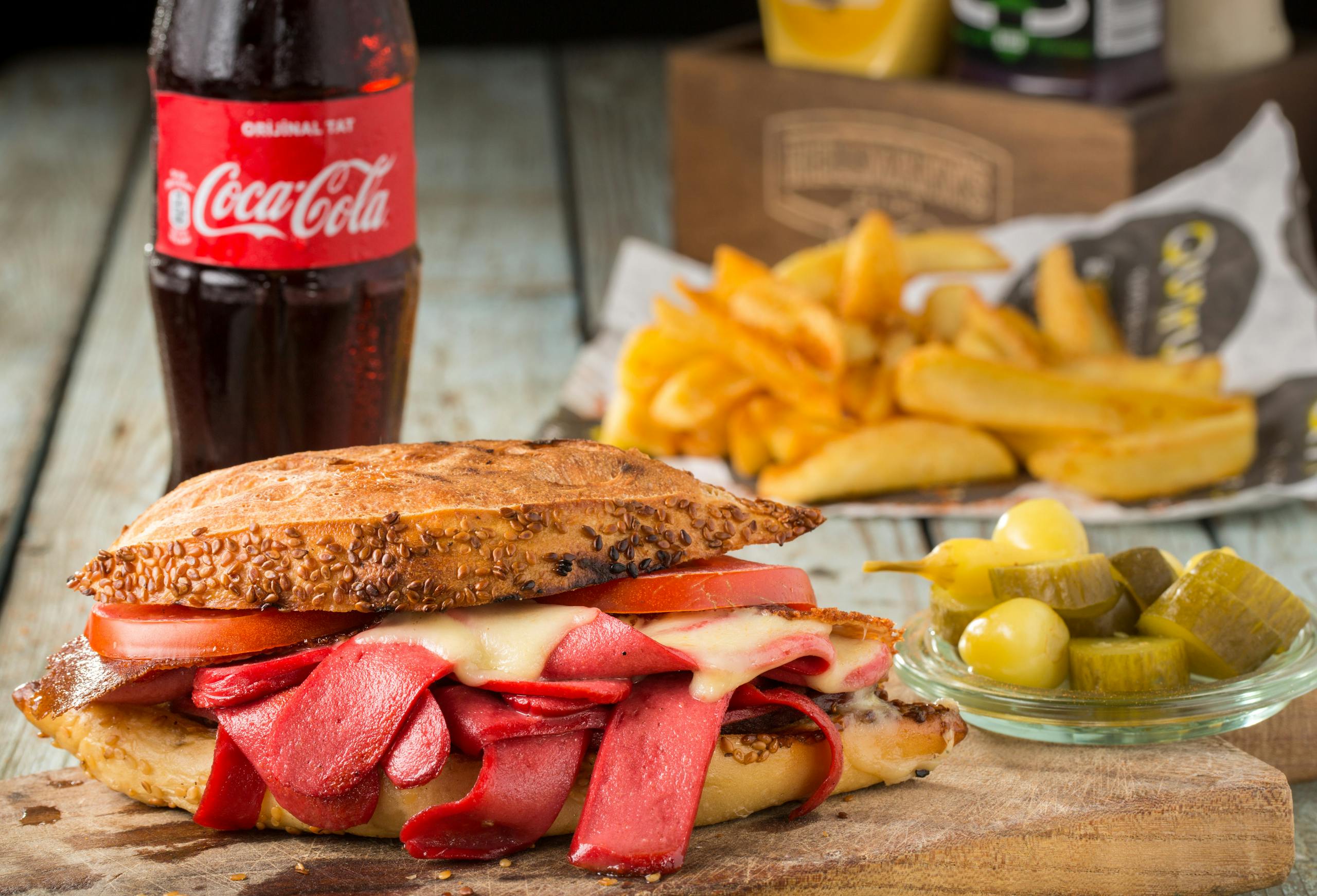 Mouth-watering sandwich with pickles and fries, served with Coca Cola in Sarıyer, Turkey.